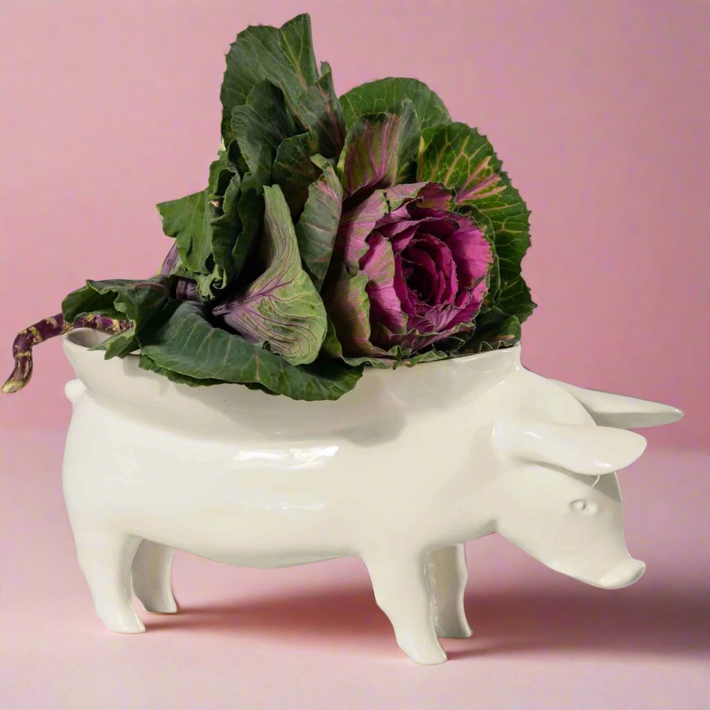 A white ceramic fruit bowl shaped like a pig, with intricate details and a curved body, perfect for displaying fresh fruit or using as a unique centerpiece in any kitchen or dining room.